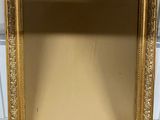a gold framed mirror sitting on top of a wooden table