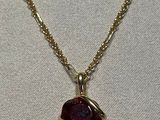 un gros plan d'un collier avec une pierre rouge sur une chaîne en or