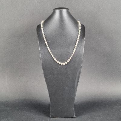 un collier de perles blanches sur un mannequin posé sur un socle noir