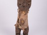 une vieille statue en bois représentant un homme debout sur une surface blanche