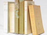 several books are stacked on top of each other on a white surface