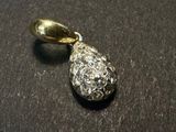 a silver and gold pendant on a black surface