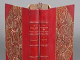 two red books with gold trims are open on a gray surface