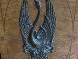 a metal sculpture of a bird that is on the wall