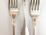 three forks and two spoons on a white table