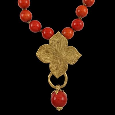 un collier composé de perles dorées et corail, orné d'un pendentif en forme de fleur