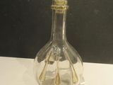 a clear glass bottle with a gold top on a table