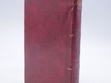 an old red book sitting on top of a white surface