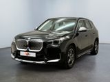 La voiture noire est garée devant un mur blanc.