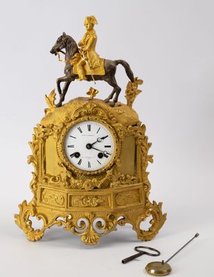 une horloge en or surmontée d'une statue représentant un homme à cheval