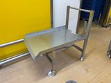 une table en acier inoxydable sur roulettes, près d'un mur jaune