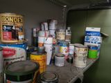 many cans of paint sitting on a shelf in a room