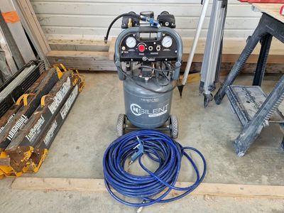 a small air compressor sitting on the floor next to a pile of tools
