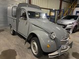 a small grey car parked in a garage next to other cars