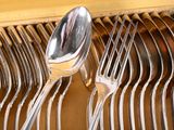 a lot of forks and spoons that are on a rack
