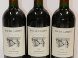 three bottles of red wine are lined up on a white surface