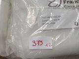 deux sacs contenant des oreillers blancs posés par terre, avec des étiquettes de prix