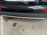 the rear end of a black car with a license plate on it ' s bumper