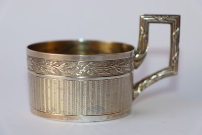 une coupe en argent munie d'une anse, posée sur un fond blanc