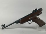 the rifle is sitting on a clear stand on a white surface