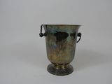 un vase en argent posé sur une surface blanche