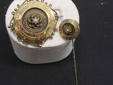 broche et épingles plaquées or sur un fond noir