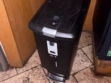 a black trash can sitting next to a television on the floor
