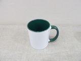 a green and white coffee mug sitting on a table