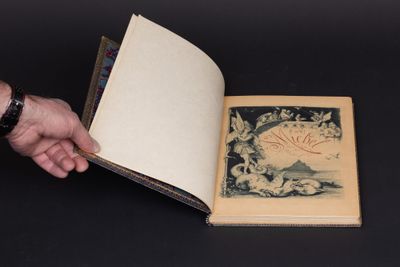 quelqu'un tient un livre ouvert sur lequel figure l'image d'un oiseau