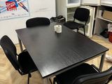 une table noire avec quatre chaises et une tasse de café posée dessus
