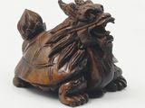 a small statue of a turtle sitting on a white surface