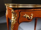 an antique wooden table with a gold decoration on top of it