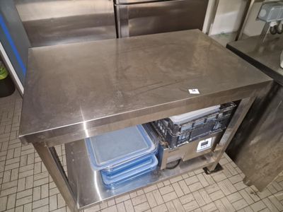 une table en acier inoxydable sur laquelle sont posés plusieurs récipients en plastique