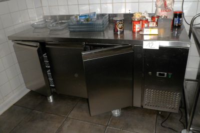 un plan de travail en acier inoxydable dans une cuisine équipée d'un réfrigérateur