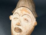 an old wooden mask with a hat on top of it