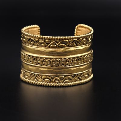 gros plan d'un bracelet en or sur une surface noire