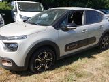 une voiture argentée garée dans un champ, avec d'autres voitures en arrière-plan