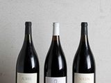 trois bouteilles de vin sont alignées sur une table en bois