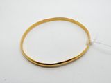 gros plan d'un bracelet en or sur une surface blanche