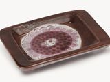 a brown and white plate with a flower design on it