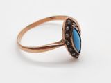 gros plan d'une bague en or avec une pierre bleue