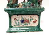 a green vase that has two birds on it