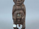 une petite statue en bois représentant un singe tenant une horloge