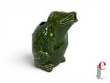a green frog figurine sitting on a white surface