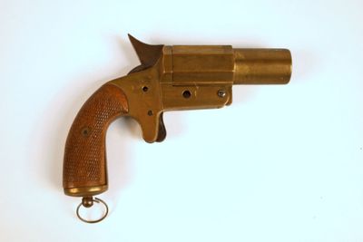 un revolver en laiton muni d'un porte-clés, posé sur une surface blanche