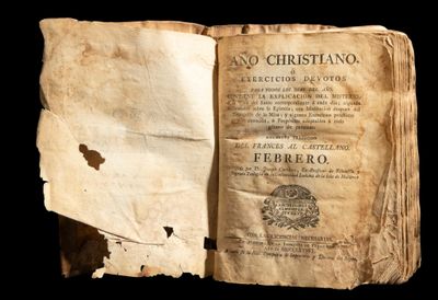 un vieux livre est ouvert sur un fond noir, avec un morceau de papier déchiré