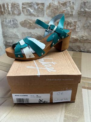 green and white sandals on a cardboard box with a brick wall in the background