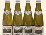 four bottles of wine are lined up in a row on a white surface