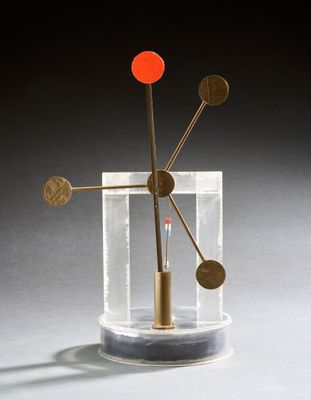 une image représentant une sculpture en métal et en verre, avec une boule rouge au centre
