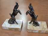 two figurines of dogs on marble blocks on a table